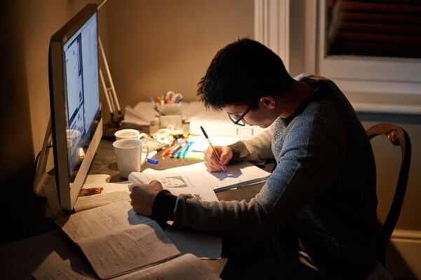 People writing and working at a shared table in soft light